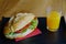Sandwich and orange juice for the breakfast prepared at home on wooden background