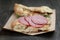 Sandwich with pita bread and salami on wood table