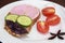 Sandwich of rye bread with delicious sausage, slices of fresh cucumber, tomato and basil leaves on a white plate