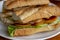 Sandwich with salad and tomatoes on white plate closeup photo. French baguette with salad on wooden table.