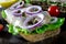 Sandwich with salted herring, butter and red onion on old rustic cutting board. Selective focus