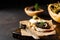 Sandwich with slice of mozzarella cheese and tapenade, caper on dark rustic table background. Traditional Provence dish.
