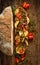 Sandwich with smoked sheep cheese, grilled zucchini, tomatoes and herbs on a wooden rustic table