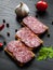 Sandwich of thinly sliced spicy salami on bread on a dark wooden background