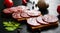 Sandwich of thinly sliced spicy salami on bread on a dark wooden background