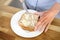 Sandwich in a white plate. Woman buttering bread. Female hands, butter and a knife. Cooking breakfast