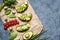 Sandwiches with avocado, spinach, guacamole, arugula and quail eggs on parchment on a concrete background. Spring food