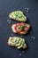Sandwiches with cream cheese, avocado, tomato and cucumber on a dark background, top view. Healthy diet food concept.