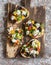 Sandwiches with feta, tomatoes, cucumbers and olives. Greek salad bruschetta style on a rustic cutting board.