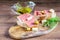 Sandwiches with fresh sliced jamon, sliced cheese, olives and green herbs on the wooden cutting board. Olive oil in the glass bowl