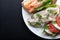 Sandwiches with ham, radish, romano salad, baby basil, mascarpone cheese, caprese salad on a black background