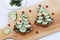 Sandwiches made of black bread, cheese and cucumber in the form of a Christmas tree decorated with berries, are placed on a wooden