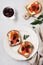 Sandwiches with smoked pink salmon olives, kalamata, microgreens and cream cheese on gray ceramic plate and trendy concrete