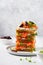 Sandwiches stack with smoked pink salmon olives, kalamata, microgreens and cream cheese on gray ceramic plate and trendy concrete