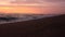 Sandy beach and beautiful waves forming the foam in the beams sunset