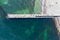 Sandy beach, concrete pier, clear sea water. Helicopter view.