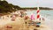 Sandy beach crowded with ses salines in ibiza and bathers by the sea in summer on the shoreline