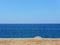 Sandy beach with crystal blue sea with lone umbrella in distance