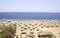 The sandy beach of Egypt with thatched umbrellas. Beautiful, wide beach with coral reef to relax on the Red sea.