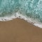 Sandy beach and foamy surf. Water wave at the edge of the beach close up