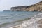 Sandy beach with gentle waves on the Cyprus coast, showcasing cliffs