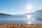 Sandy beach and lake with blue sky, sunshine, and view of distant mountains