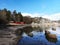Sandy beach meeting the water at Ranvika, Norway, with trees, cliffs, and three red cabins