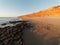 Sandy beach with Orange colour seaside cliffs at sunset glow