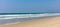 Sandy beach panoramic view. Blue clear sky, blue sea