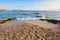 sandy beach with rocks. sunny morning in the resort town. wave brings seaweed on the stones on the shore