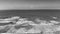 Sandy beach with rolling waves on a sunny day in grayscale