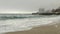 Sandy beach and rough sea,pier and high-rise hotel building in fog,dense clouds