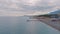 Sandy beach at sunset. Seascape. Pier. Cloudy sky. Mountains in the background. Aerial view