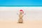 Sandy Christmas Snowman in red Santa hat at beach sand against o