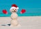 Sandy Christmas snowman in red Santa hat and mittens without sunglasses. Beach Snowman.