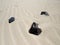 Sandy desert bottom with three black volcanic rocks. Aerial view of volcanic black rocks in the sand. Porous lava stones of