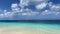 Sandy deserted tropical beach with turquoise sea and blue sky with clouds.