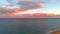 Sandy dunes beach seaside view from top. Drone point of view coastline Mediterranean Sea surf, pink bright fluffy clouds evening