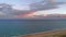 Sandy dunes beach seaside view from top. Drone point of view coastline Mediterranean Sea surf, pink bright fluffy clouds evening