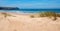 Sandy dunes Bordeira beach with grass, ocean with waves at the horizon, West algarve portugal