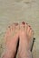 Sandy feet with red toenails on the beach