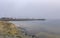 Sandy Pacific Ocean beach and a fishing pier in Half Moon Bay near San Francisco on a foggy day, boats in the background