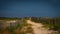 Sandy path between rustic wooden fences and wild vegetation