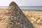 Sandy pyramid with shells on a sea beach