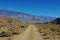 Sandy road through rocks to high mountains