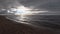 Sandy sea beach at sunset. Calm blue sea under stormy skies