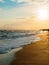 sandy seashore, foamy waves at sunset - landscape