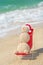 Sandy snowman in santa hat sunbathing in beach lounge.