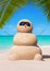 Sandy snowman in sunglasses at tropical sunny ocean palm beach.
