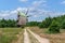 A sandy, well-trodden road leads to a mill at the edge of the forest.